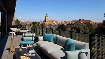 Terraza en la azotea con un conjunto de sofás, una mesa de comedor y vistas a una torre de iglesia.