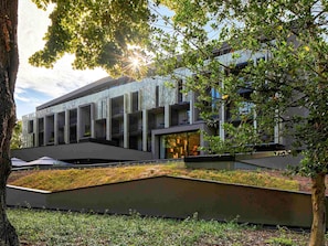 Un edificio moderno con tetto piatto, ampie finestre e un giardino pensile verde.