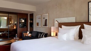 A hotel room with a large bed, a sofa, a bedside table, a mirror, and artwork on the wall. - L'Esquisse Hotel & Spa Colmar - MGallery Collection (Colmar)