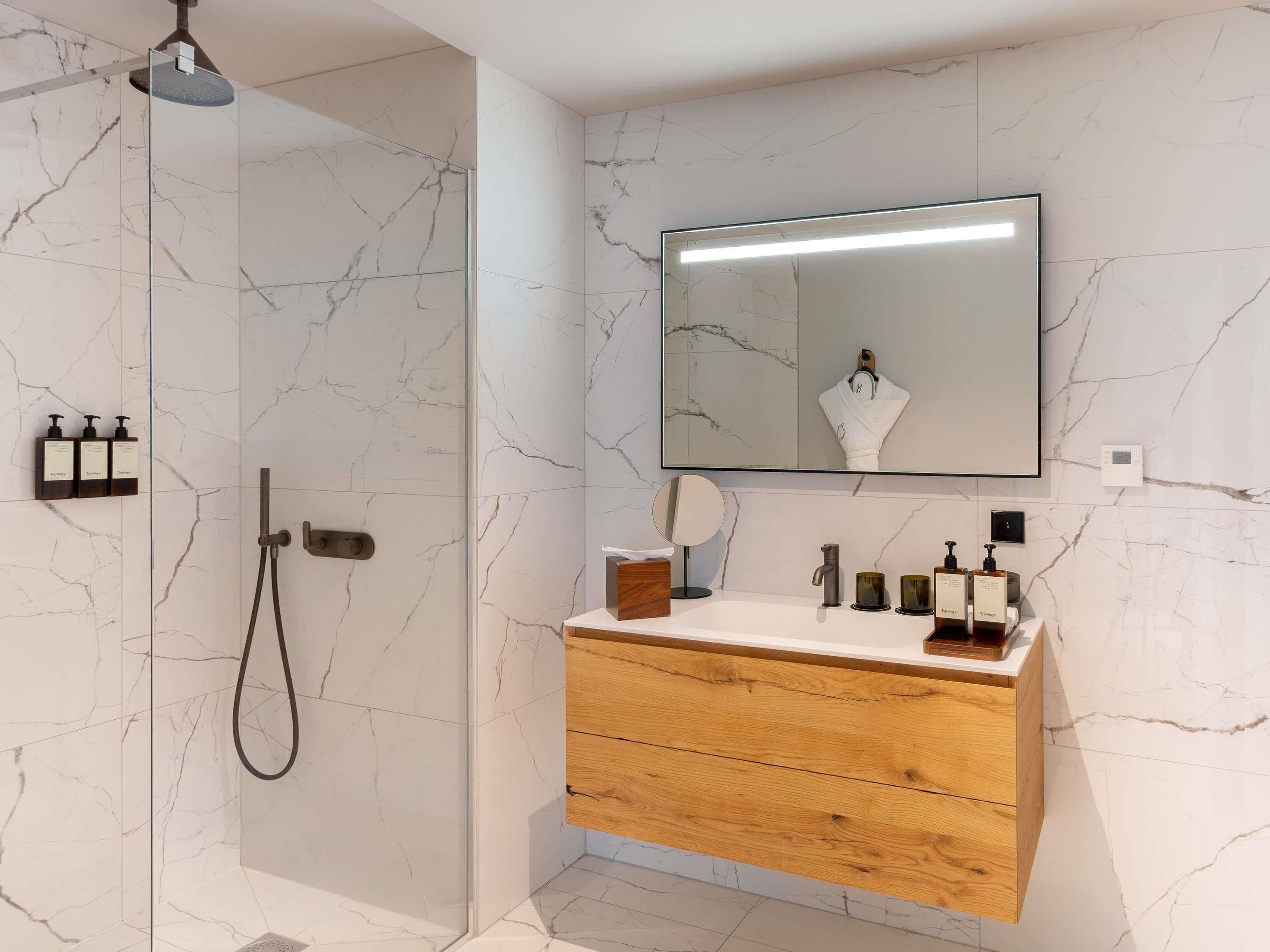 A modern bathroom with a shower, vanity, and a large mirror.
