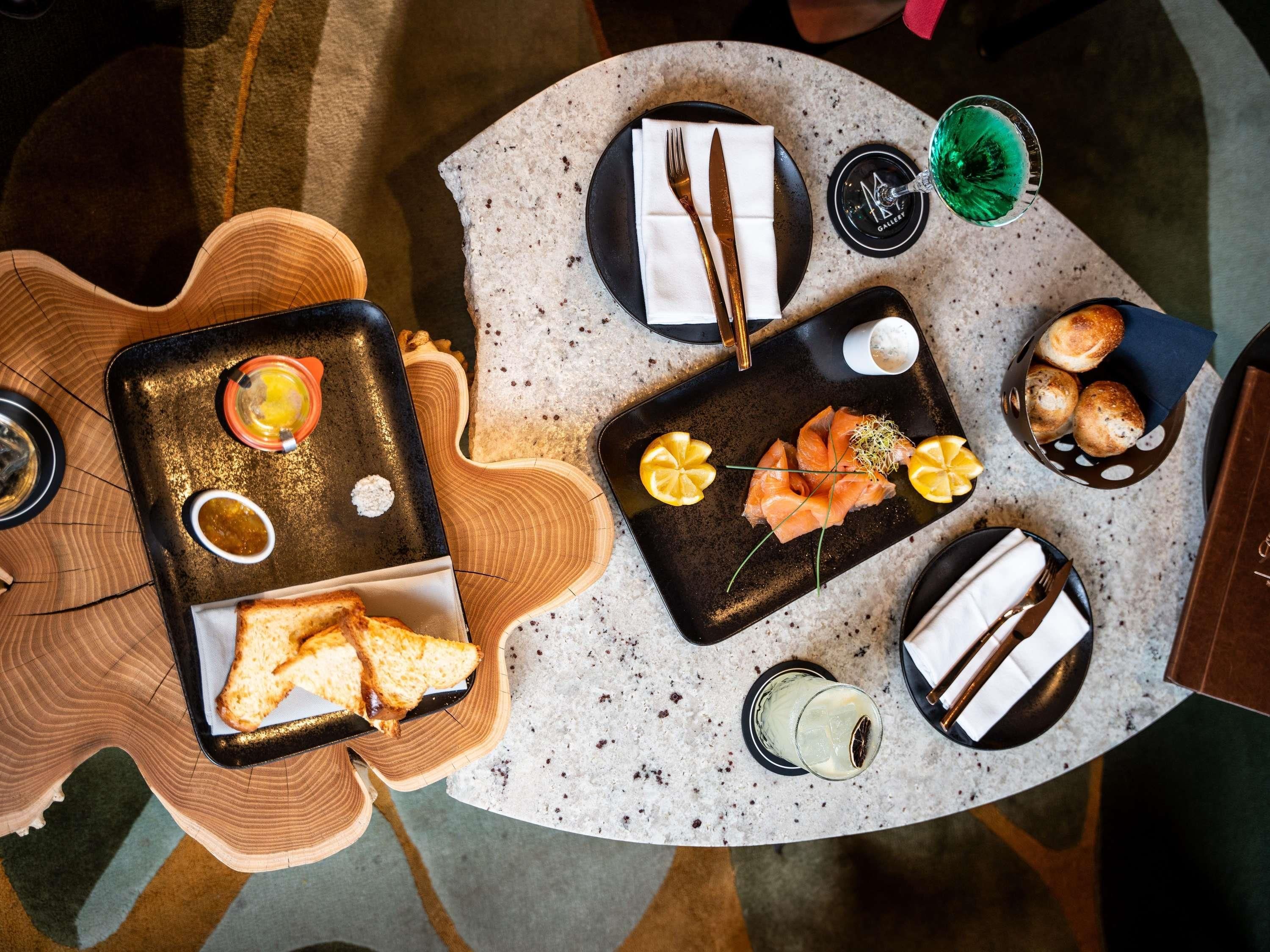 Una mesa de comedor con diversas opciones de comida, como salmón, pan y bebidas.