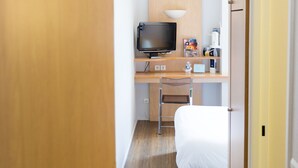 A hotel room with a bed, a desk with a television, and a door labeled with the number 106. - Hôtel Inn Design Grenoble Eybens Parc des Exposition (Eybens)