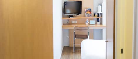 A hotel room with a bed, a desk with a television, and a door labeled with the number 106.