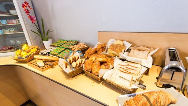 A breakfast buffet with various breads, pastries, and fruits. - Hôtel Inn Design Grenoble Eybens Parc des Exposition (Eybens)