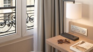 A hotel room with a large window, a desk with a lamp, a pair of sunglasses, and a book. - Timhotel Paris Gare de l'Est (Paris)