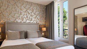A hotel room with two beds, a large window with a view of greenery, and a mirror on the wall. - Timhotel Paris Gare de l'Est (Paris)