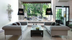 A modern living room with two sofas, a coffee table, and a large window with a view of the outdoors. - Le Prieure - Relais & Chateaux (Villeneuve-les-Avignon)