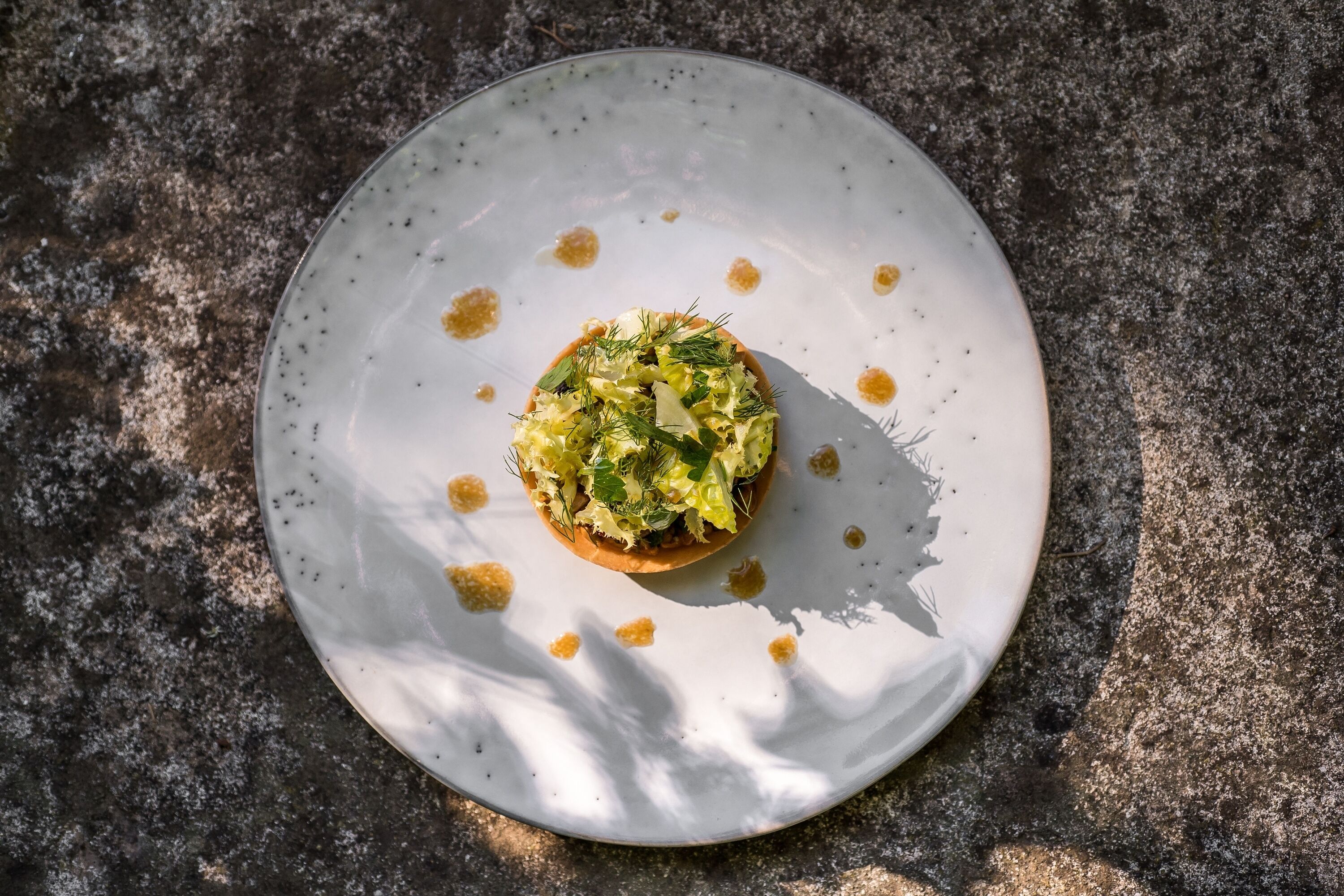 Un plato redondo y blanco con un alimento sobre una superficie texturizada.