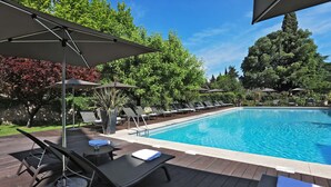 A poolside area with lounge chairs, umbrellas, and a clear blue pool. - Le Prieure - Relais & Chateaux (Villeneuve-les-Avignon)