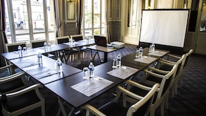 Une salle de conférence équipée d’une grande table, de chaises, de bouteilles d’eau et d’un écran de projection.