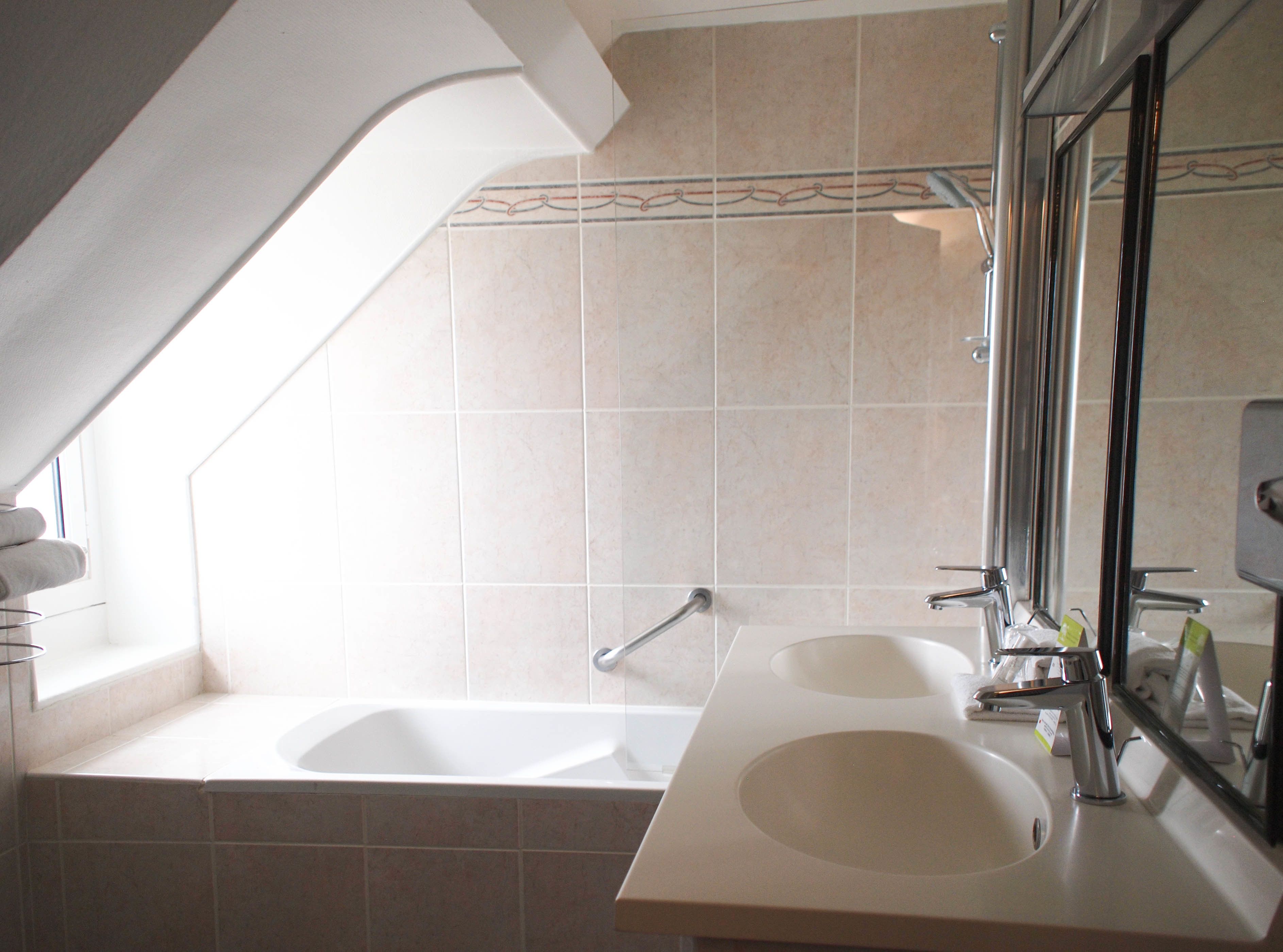 A bathroom with a bathtub, two sinks, and a large mirror.