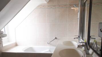 A bathroom with a bathtub, two sinks, and a large mirror.