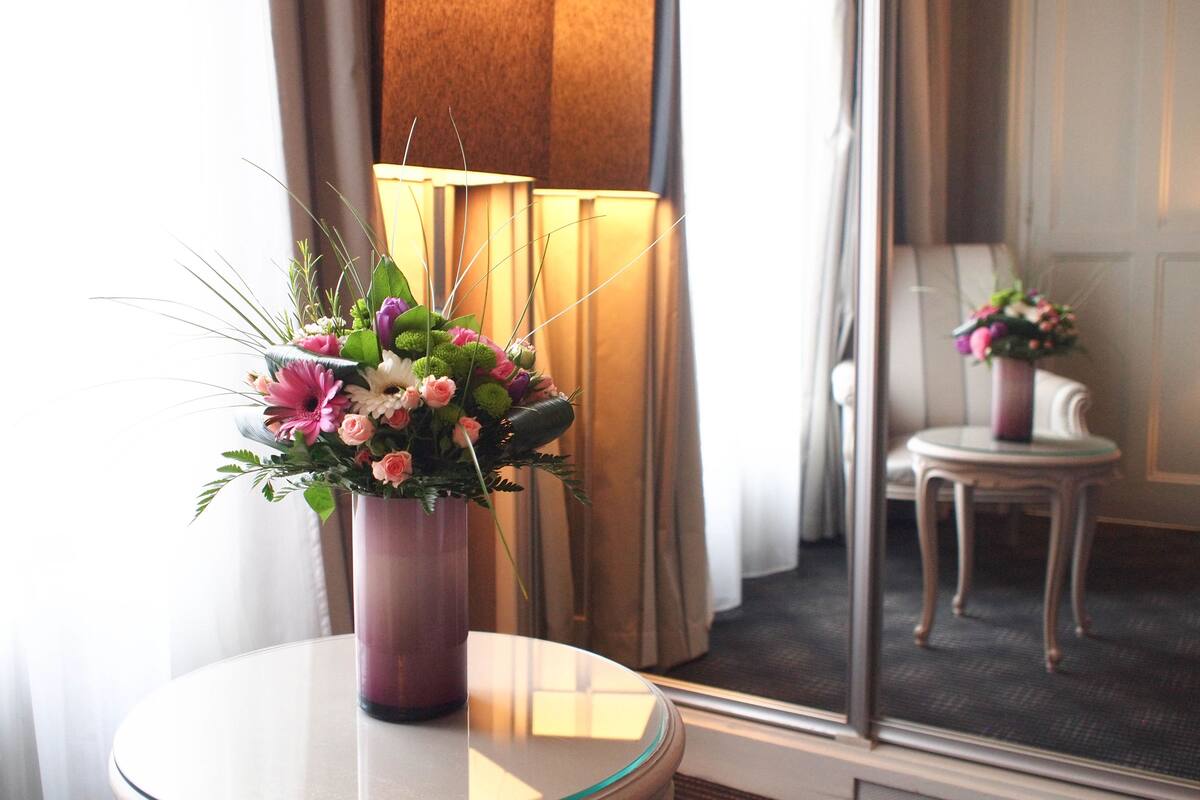 Una habitación con una mesa redonda de vidrio que sostiene un jarrón morado con un arreglo floral.