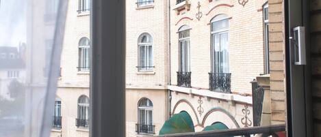 A view of a building with multiple windows and balconies, featuring a brick facade and decorative ironwork.