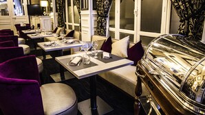 Un restaurant avec des tables dressées pour le service, des chaises et un coin bar.