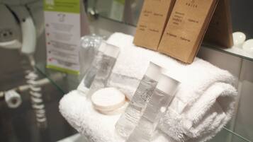 Une salle de bain avec une douche à parois de verre, des articles de toilette disposés sur une serviette blanche, et deux boîtes marron étiquetées « TRITA ».