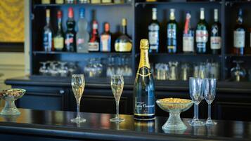 Un bar avec une bouteille de champagne, deux verres et un bol de noix sur le comptoir.