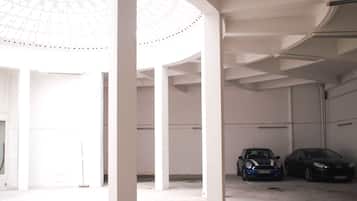 Un ambiente spazioso e luminoso, con soffitto alto e un lucernario circolare. Due auto sono parcheggiate in primo piano.