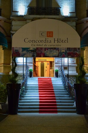 The entrance to Concordia Hotel with a red carpet leading up the stairs.