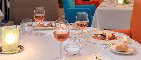 A dining table set with plates of food, glasses of wine, and a candle.
