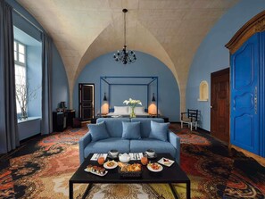 A room with a blue sofa, a coffee table with breakfast, a chandelier, and a blue door. - Jules César Hotel & Spa Arles - MGallery Collection (Arles)