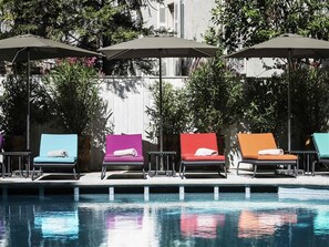 Una piscina al aire libre, sillones reclinables de piscina