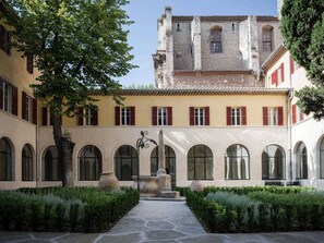 A courtyard with a central fountain, surrounded by arched windows and a building with red shutters. - Jules César Hotel & Spa Arles - MGallery Collection (Arles)