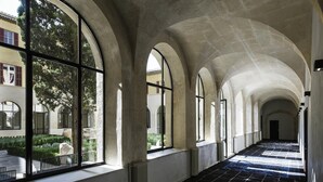A corridor with arched windows and a tiled floor. - Jules César Hotel & Spa Arles - MGallery Collection (Arles)