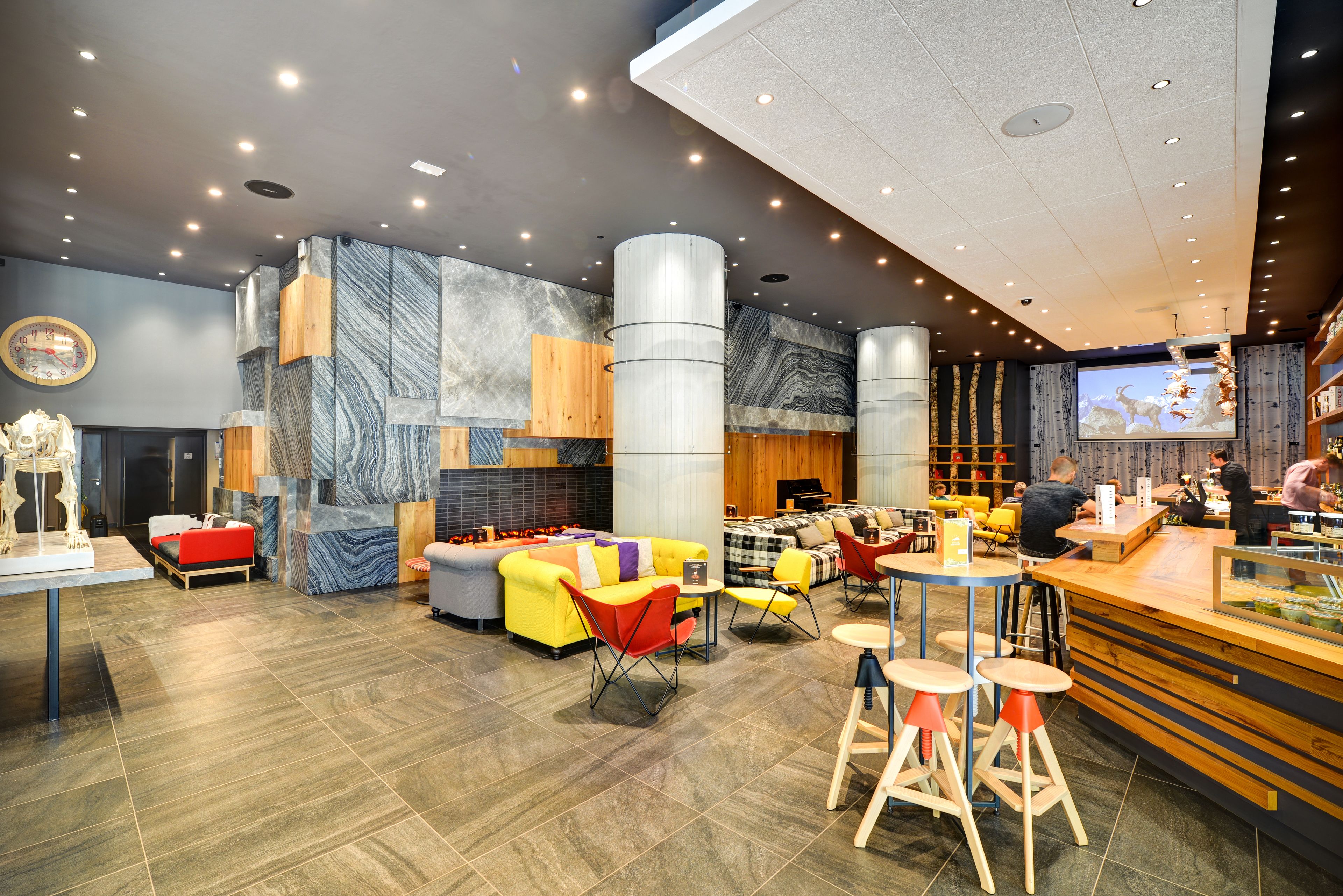 A modern interior with seating areas, a bar, and a large screen.