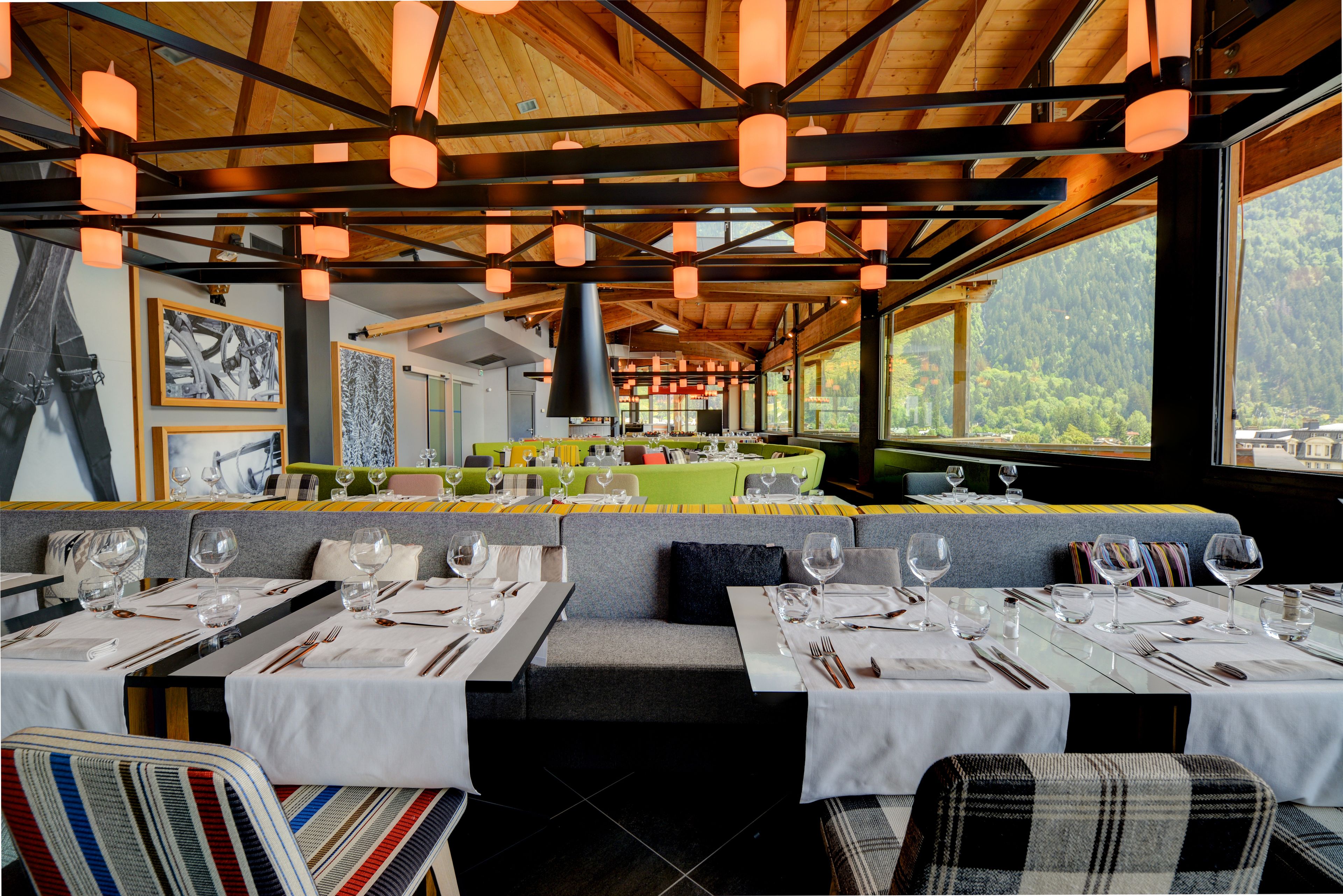 A restaurant with a wooden ceiling, large windows, and tables set for dining.