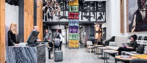 A modern lobby with a reception desk, seating area, and a vertical display of colorful fabric.