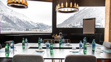 A conference room with a large table, chairs, water bottles, and a view of snow-covered mountains.