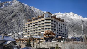 Ein mehrstöckiges Hotel mit einer zentralen Atriumhalle, umgeben von schneebedeckten Bergen.