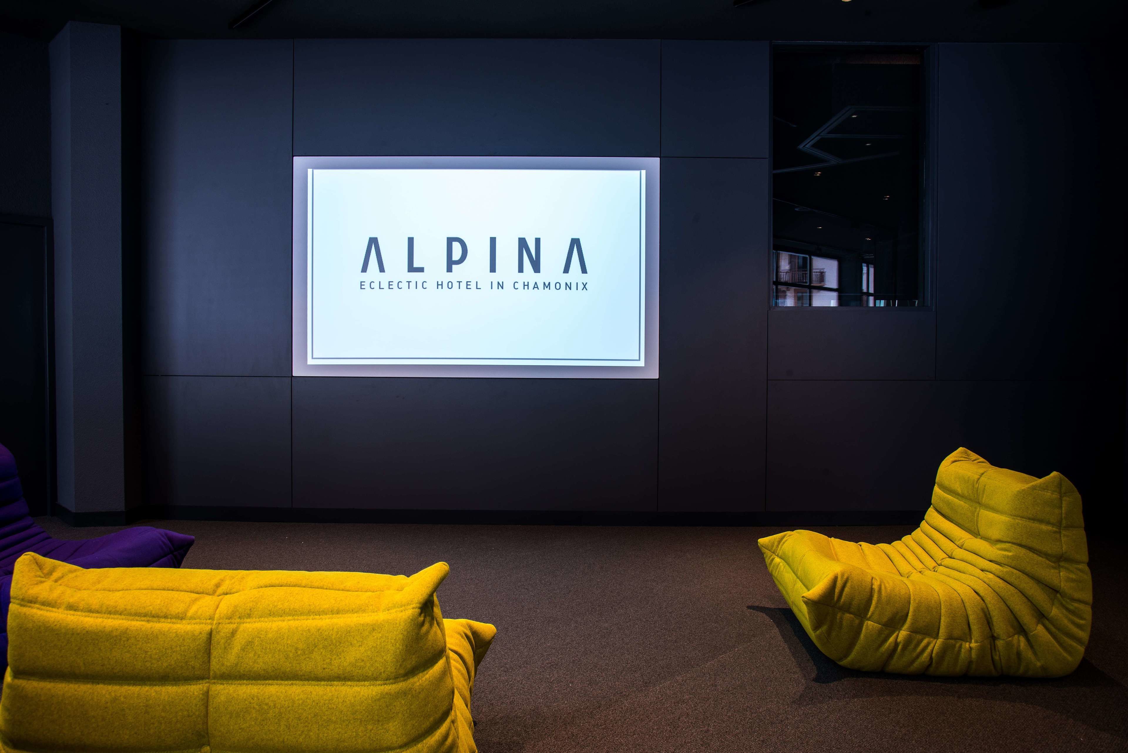 A modern interior with a large illuminated sign reading "ALPINA ELECTRIC HOTEL IN CHAMONIX" and two yellow bean bag chairs.