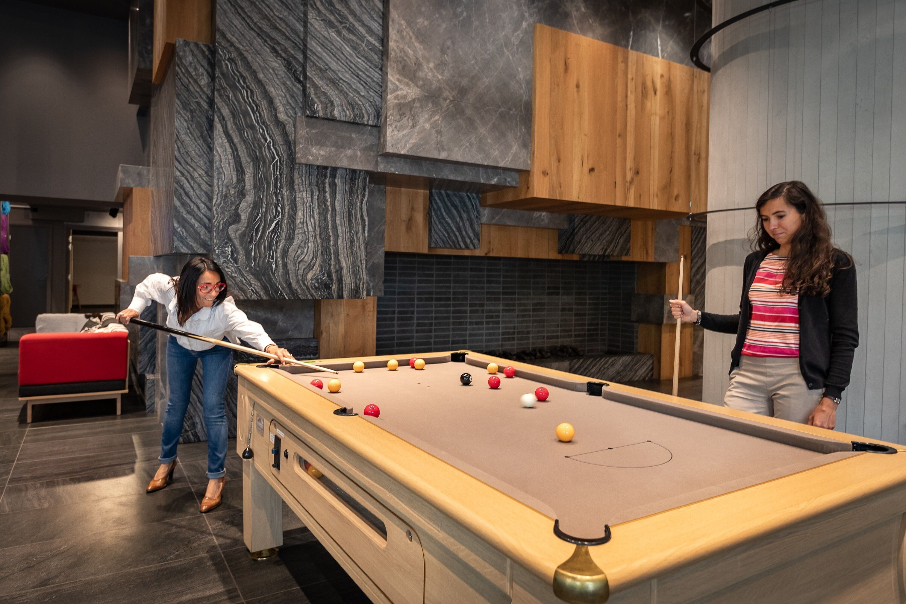 A pool table in a modern room with wooden and marble accents.