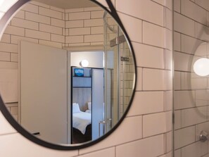 A bathroom with a mirror reflecting a room with a bed and a nightstand. - Ibis Grenoble Gare (Grenoble)