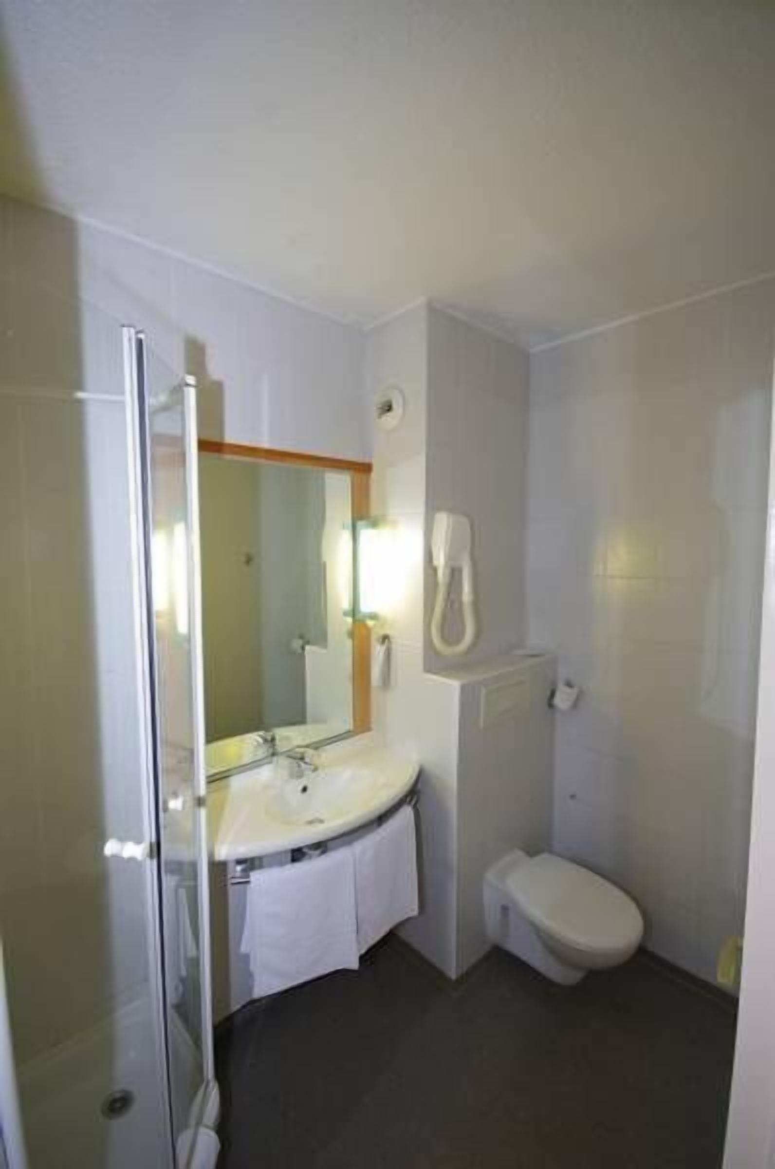 A small bathroom with a glass shower enclosure, a white sink, and a toilet.