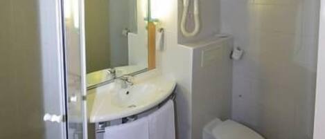 A small bathroom with a glass shower enclosure, a white sink, and a toilet.