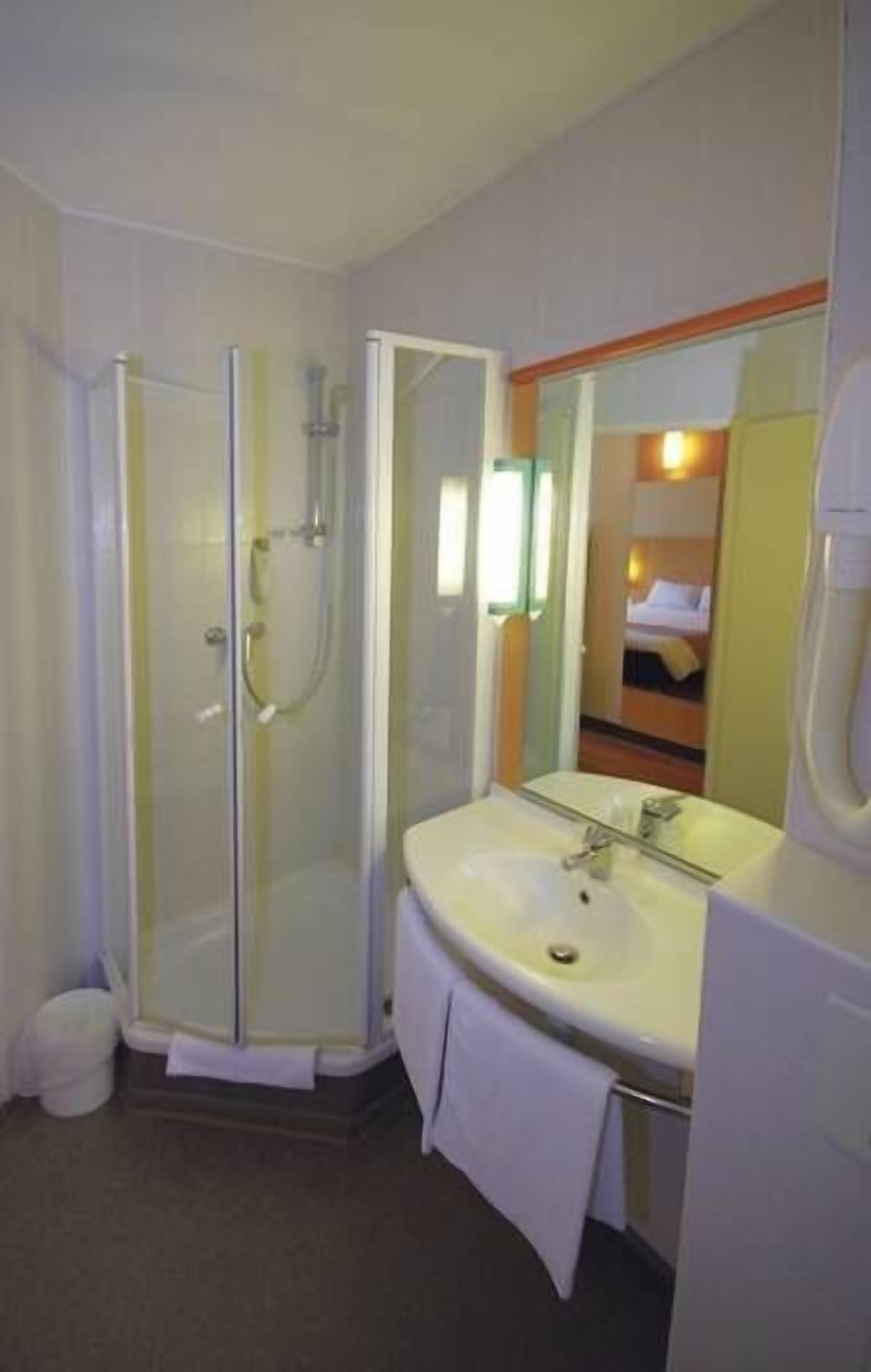 Un baño con cabina de ducha de vidrio, lavamanos y espejo.