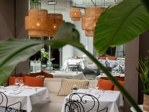 A restaurant with round tables, orange cushions, and wicker pendant lights. - Hôtel de Sers (Paris)