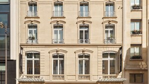 Un immeuble à plusieurs étages doté d’éléments architecturaux classiques, notamment des balcons richement décorés et de grandes fenêtres.