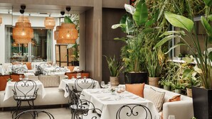 Un restaurant doté de nombreuses tables, de chaises et de luminaires suspendus.