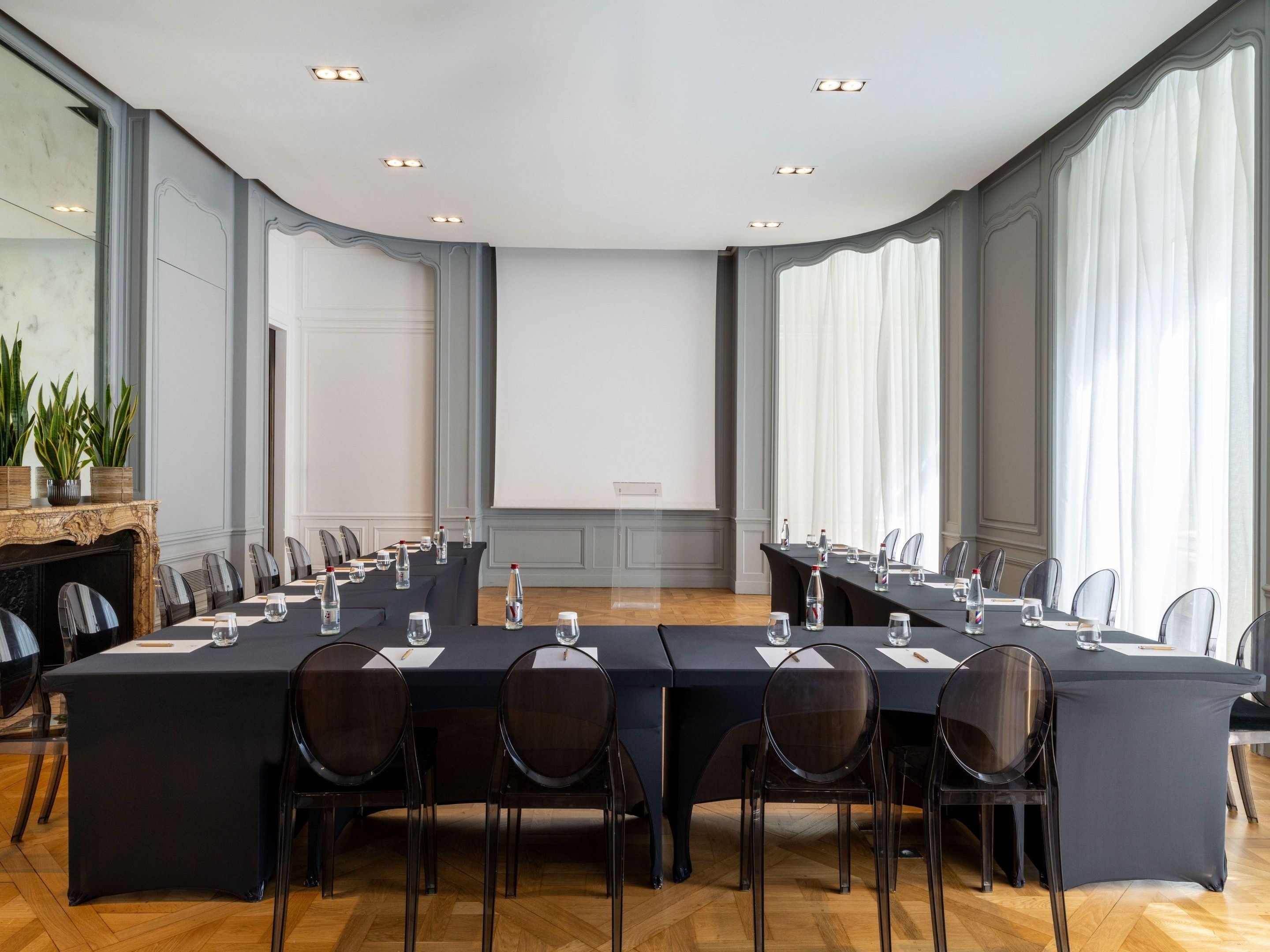 Une salle de conférence équipée d’une longue table, de chaises, d’un écran de projection et d’une cheminée.