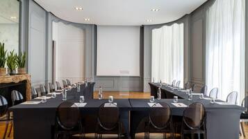 Une salle de conférence équipée d’une longue table, de chaises, d’un écran de projection et d’une cheminée.