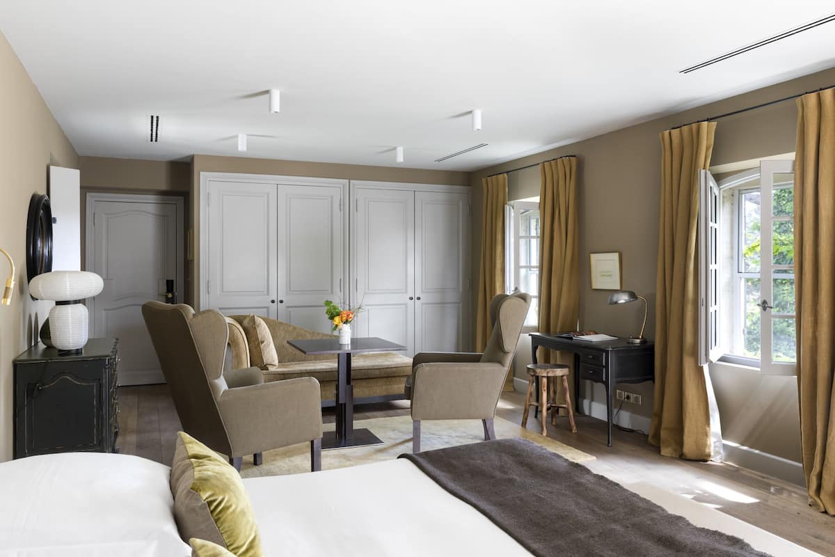 A spacious bedroom with a large bed, a desk, and a comfortable seating area.