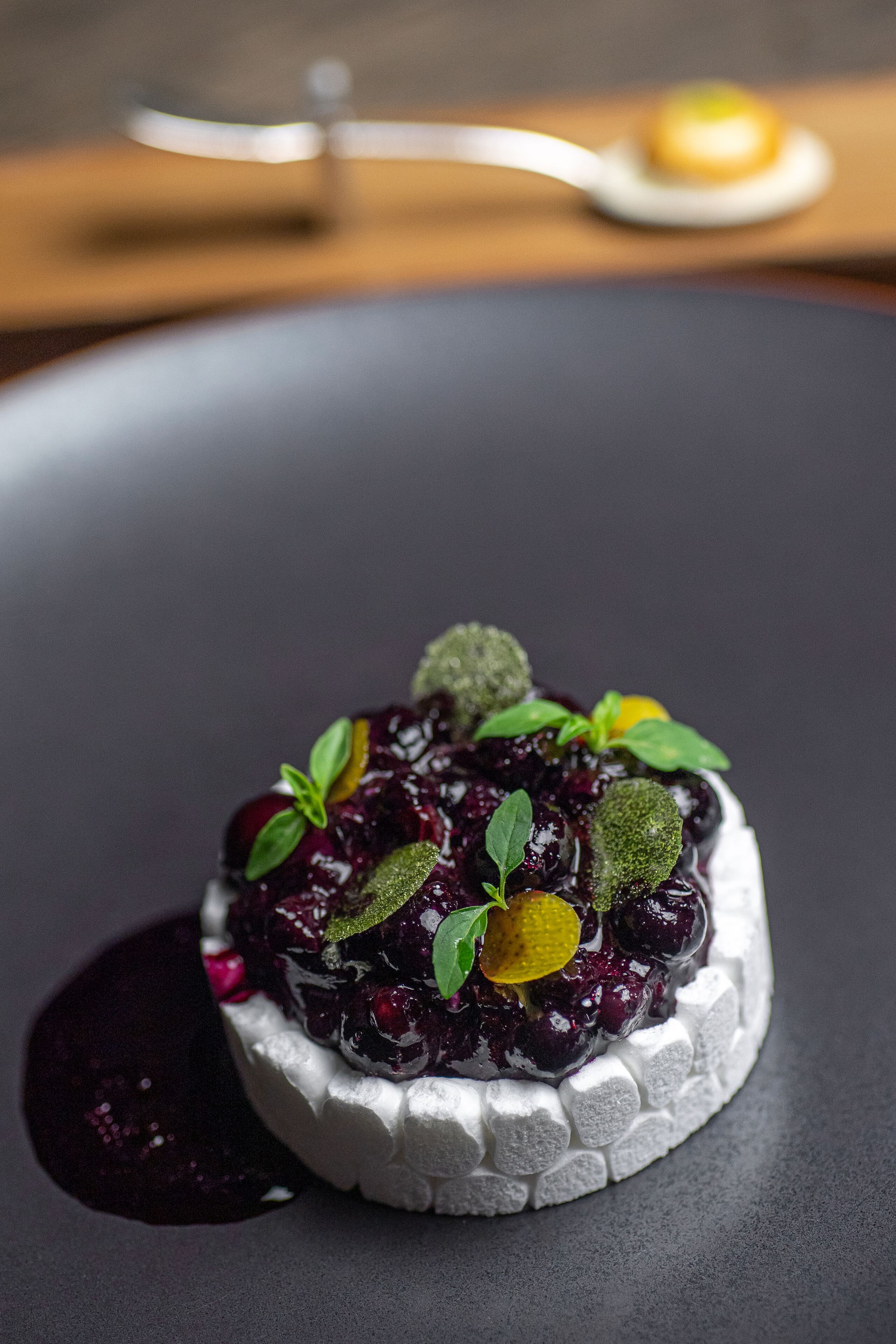 Un postre sobre un plato oscuro, con una cuchara al fondo.