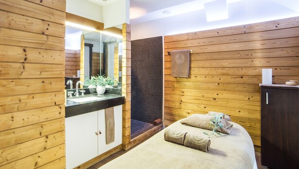 A wooden-paneled room with a bed, a sink, and a mirror.