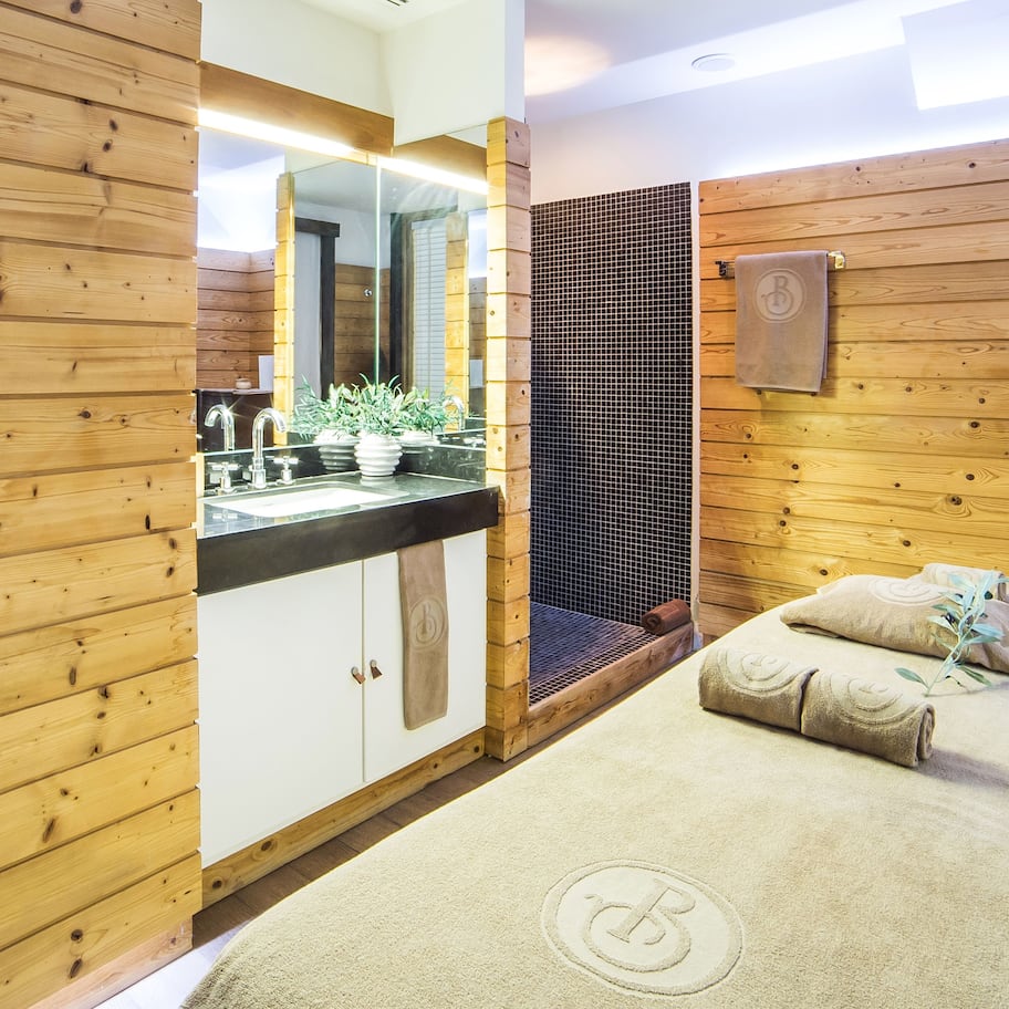 A wooden-paneled room with a bed, a sink, and a mirror.