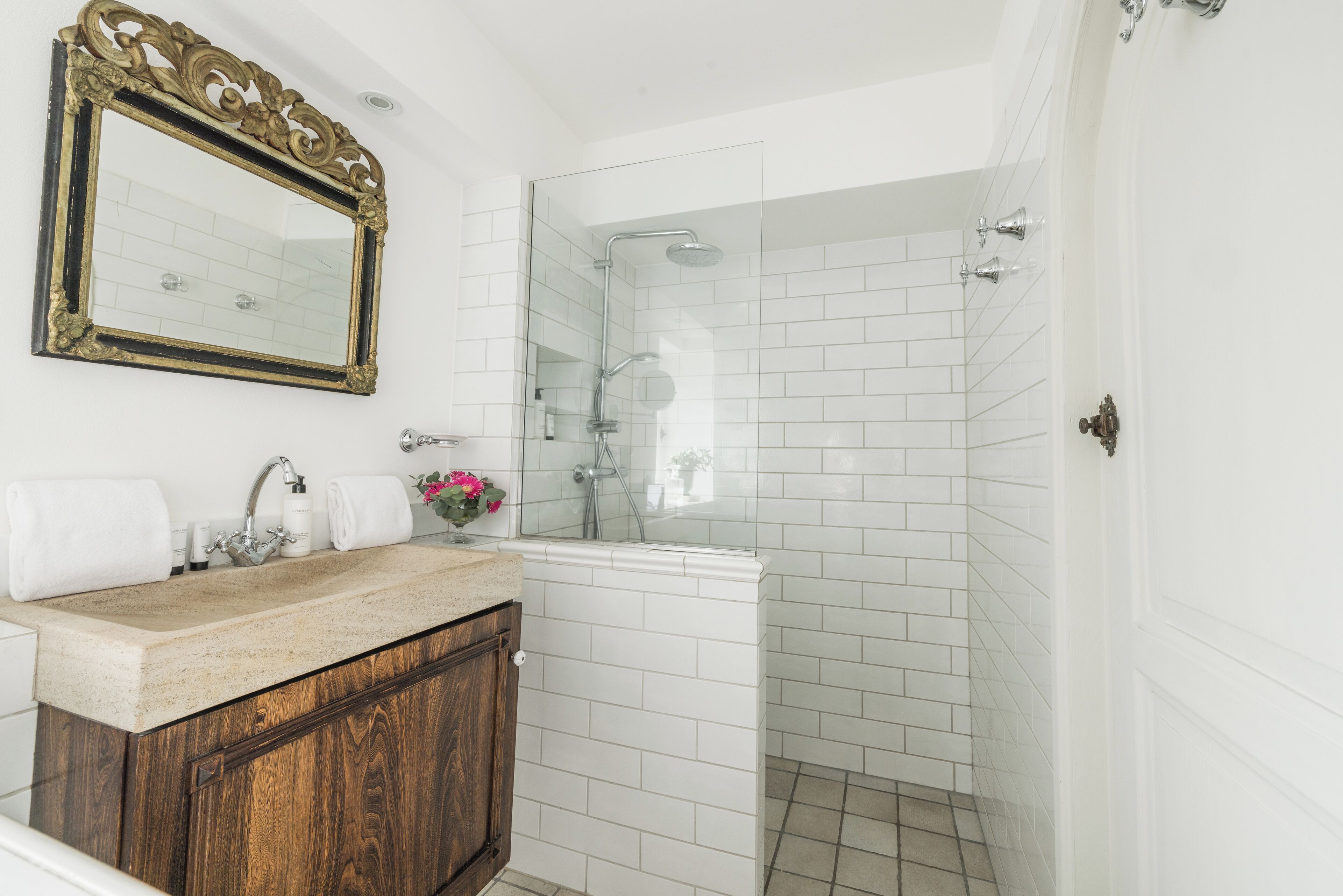 Une salle de bain avec un meuble-lavabo en bois, un grand miroir et une douche à parois de verre.