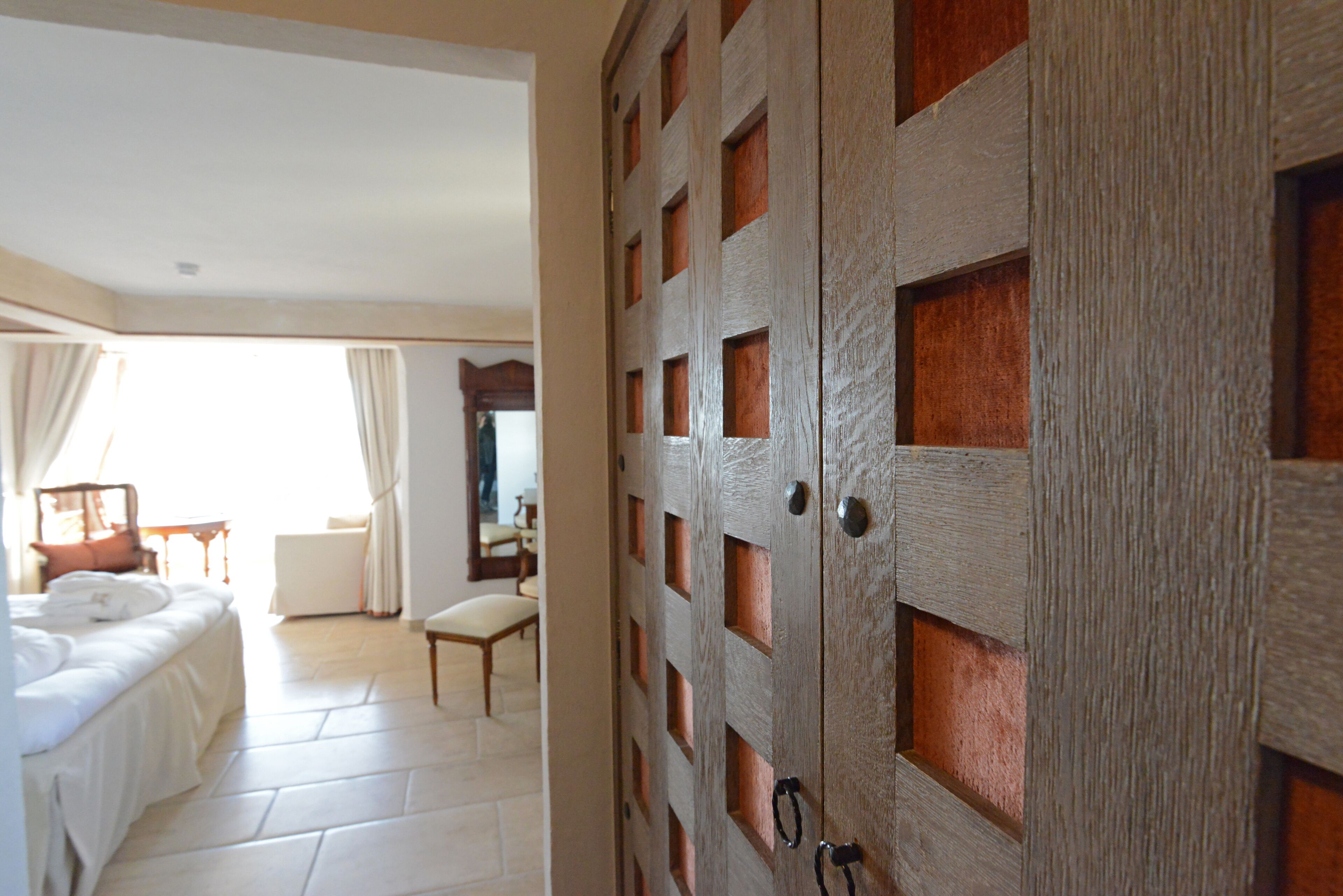 Habitación de hotel con una cama, una silla, un escritorio y un armario de diseño calado.